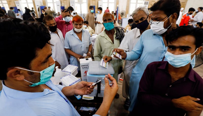 In this picture, people gather to receive their COVID-19 vaccine doses at a vaccination centre in Karachi — Reuters