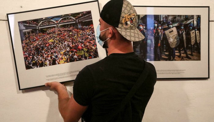 A worker hangs photos for the exhibition Anonymous photographer in Myanmar ahead of the Visa pour lImage international photojournalism festival in Perpignan, France. AFP