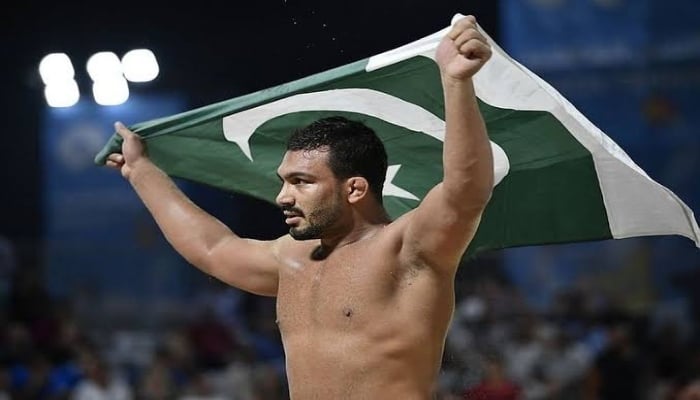 Pakistani wrestler Inam Butt holds up the national flag after victory. Photo: Twitter