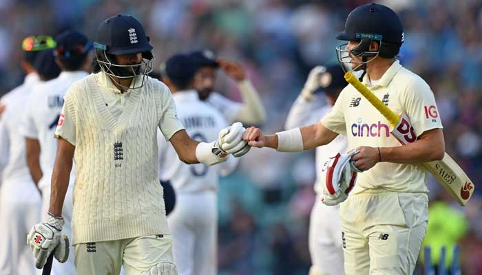Englands Haseeb Hameed (L) and Englands Rory Burns (R) gesture during their opening stand during play on the fourth day of the fourth cricket Test match between England and India at the Oval cricket ground in London on September 5, 2021. — AFP