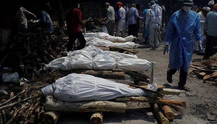 A health worker wearing personal protective equipment (PPE) walks past the funeral pyres of those who died from the coronavirus disease (COVID-19) during a mass cremation at a crematorium in New Delhi, India, April 26, 2021. &mdash; Reuters/File
