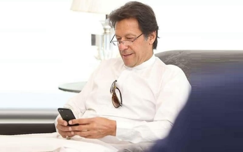 PM Imran Khan smiles as he scrolls through his phone. Photo: File