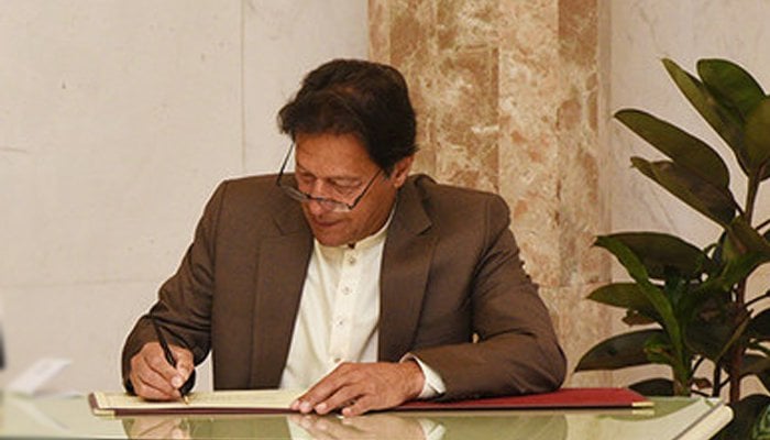 Prime Minister Imran Khan signing a document. Photo: File/ Geo Urdu