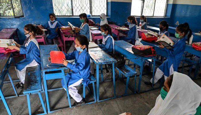 Schoolchildren sit in a class, studying their textbooks. Photo: The News International