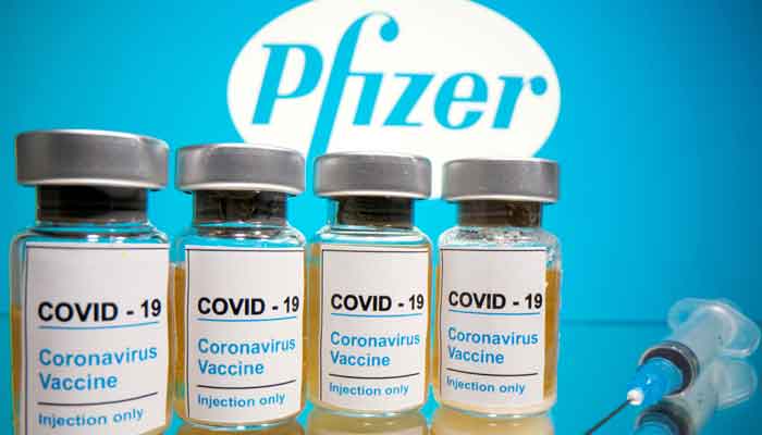 Vials with a sticker reading, COVID-19 / Coronavirus vaccine / Injection only and a medical syringe are seen in front of a displayed Pfizer logo in this illustration taken October 31, 2020. Photo: Reuters