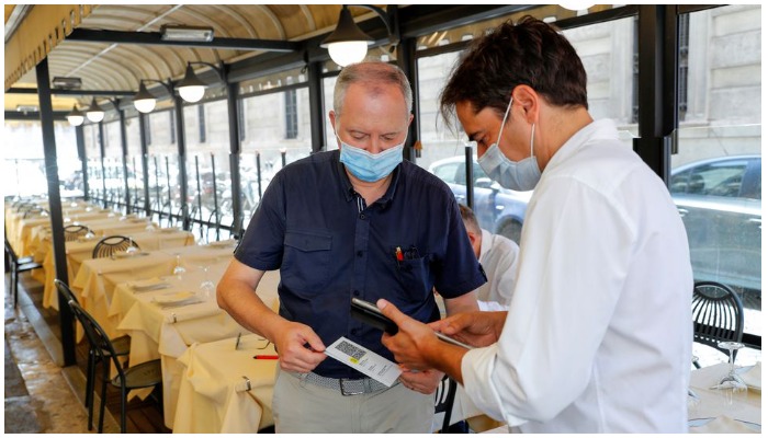 A man has his Green Pass (health pass) checked before entering a restaurant as Italy brings in tougher restrictions REUTERS/Remo Casilli