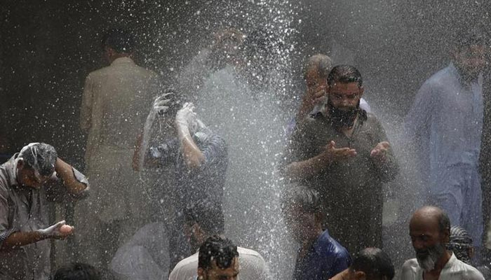 People are seen bathing while others cool off from the heat as they are sprayed with water jetting out from a leaking water pipeline in Karachi, Pakistan, June 25, 2015. — Reuters/File