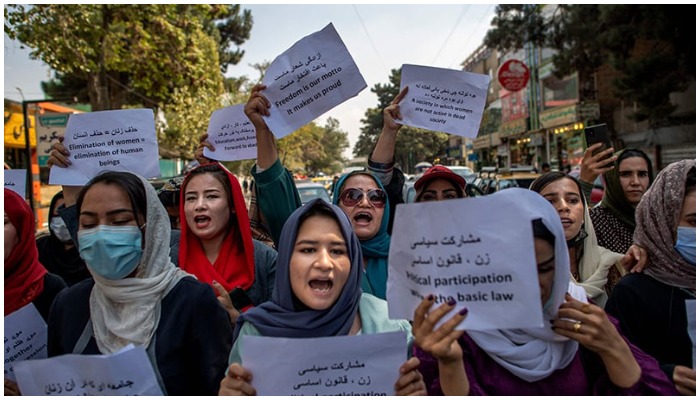 Afghan women converse with a man while they hold placards during a demonstration demanding better rights for women in front of the former Ministry of Women Affairs in Kabul on September 19. — AFP