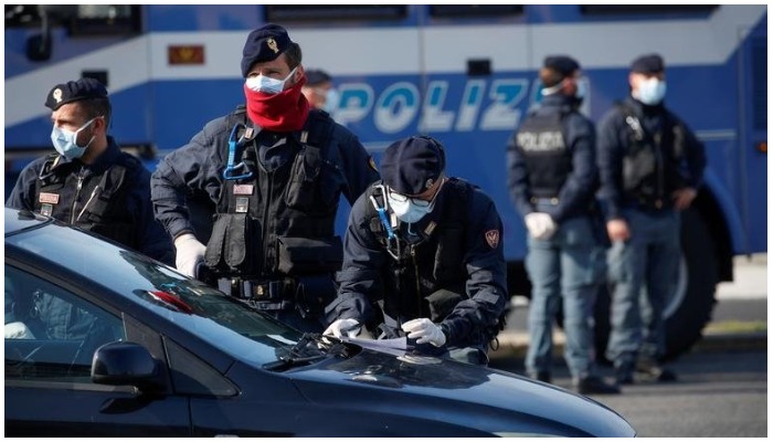 Police officers wearing protective face masks check documents of drivers COVID-19 outbreak in Ostia, near Rome, Italy, April 13, 2020. — Reuters File