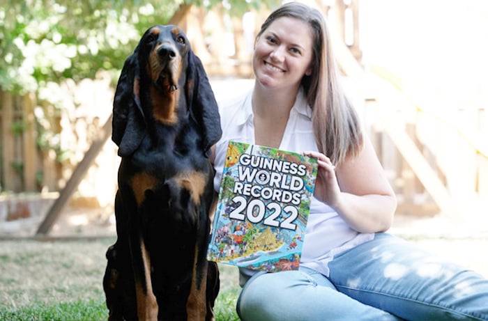 Paige Olsen, Lous owner, poses with her pup with a copy of the Guinness World Records 2022: Photo: Courtesy Guinness World Records