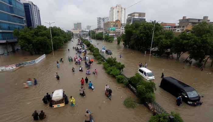 People wade through a flooded road amidst submerged vehicles during monsoon rain in Karachi, August 27, 2020. — Reuters