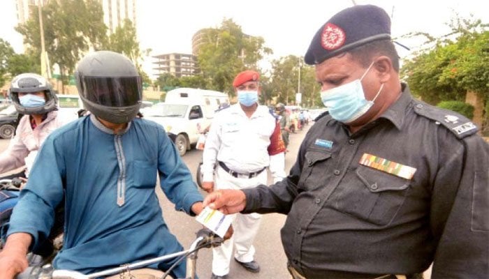 A file photo of a police officer checking the COVID-19 vaccination card of a citizen in Karachi.
