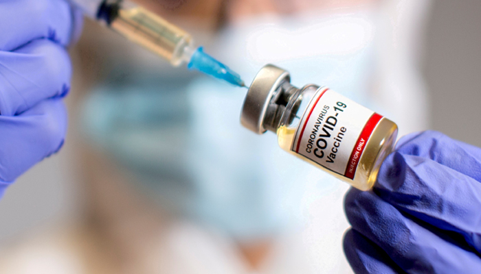 A woman holds a small bottle labelled with a Coronavirus COVID-19 Vaccine sticker and a medical syringe in this illustration taken October 30, 2020. — Reuters