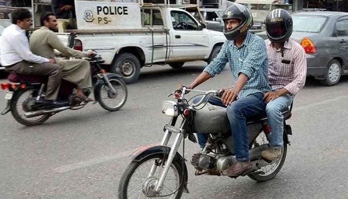 Two men travel on a motorcycle at a busy road, somewhere in Pakistan. Photo: File