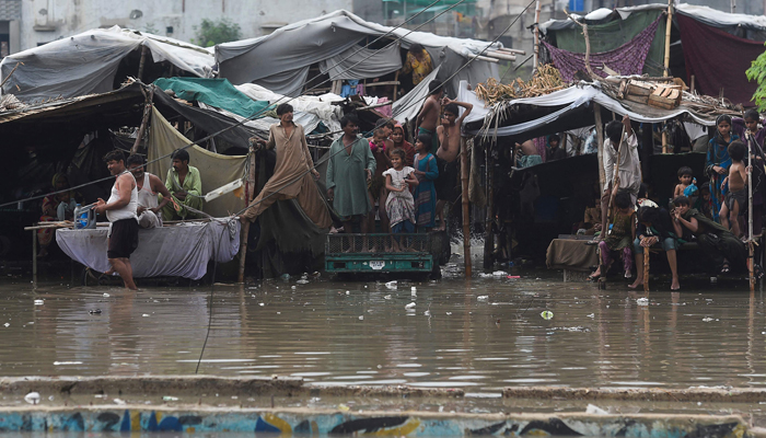 Homeless people shelter on their makeshift homes alongside a flooded street after heavy rainfall in Karachi on September 23, 2021. — AFP/File
