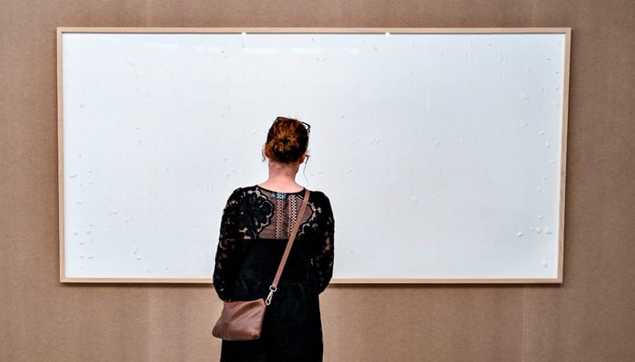 A woman stands in front of an empty frame hung up at the Kunsten Museum in Aalborg, Denmark, on September 28 2021. — AFP