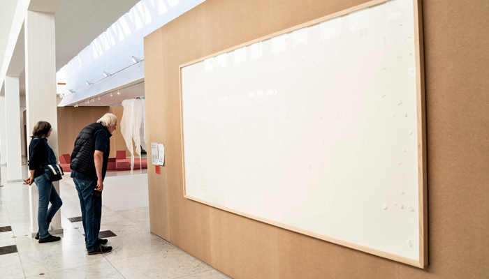 People stand in front of an empty frame hung up at the Kunsten Museum in Aalborg, Denmark, on September 28 2021. — AFP