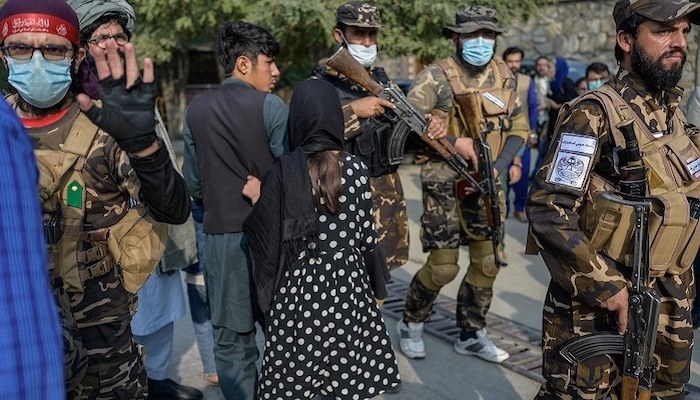 A Taliban fighter (left) makes a hand gesture asking the photojournalists to stop covering a demonstration by women protesters in Kabul. Photo: AFP