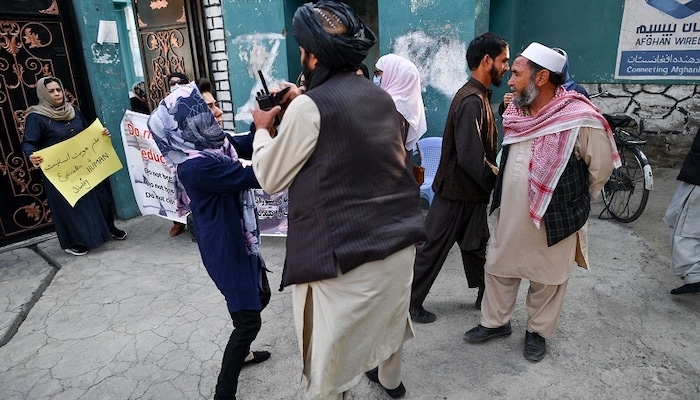 A woman protester scuffles with a member of the Taliban during a demonstration outside a school in Kabul. Photo: AFP