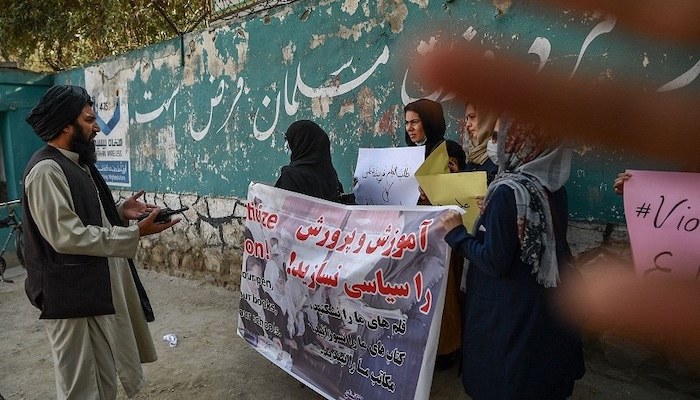 A member of the Taliban speaks with women protesters as another tries to block the view of the camera with his hand during a demonstration held outside a school in Kabul. Photo: AFP