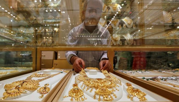 A shopkeeper can be seen arranging gold sets in his shop. — Reuters/File