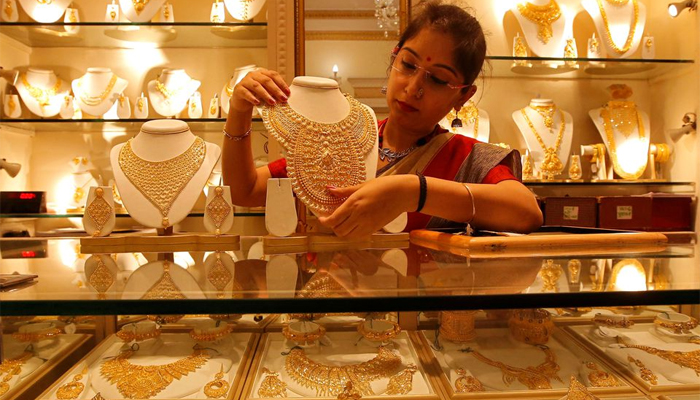 A saleswoman displays a gold necklace inside a jewellery showroom. — Reuters