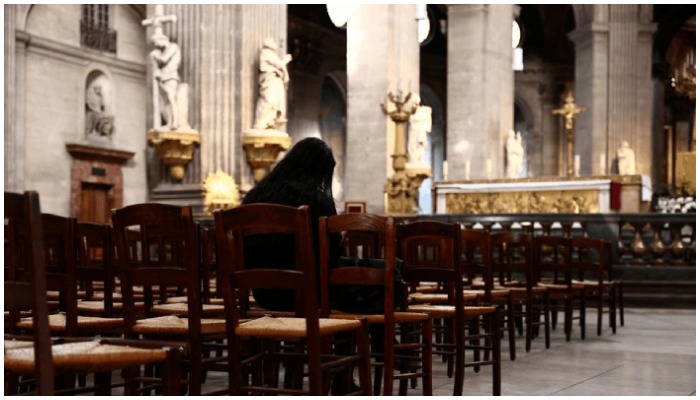 A woman prays inside the Saint-Sulpice Church in Paris, France — Reuters