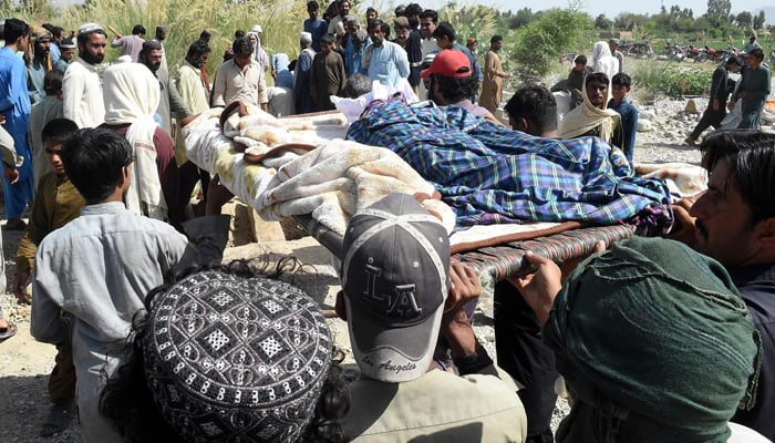 Residents carry the body of an earthquake victim as they prepare for an earthquake burial in the remote mountainous district of Harnai on October 7, 2021. - AFP