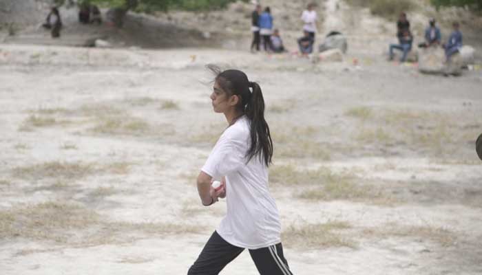 A girl prepares to bowl during the cricket tournament.