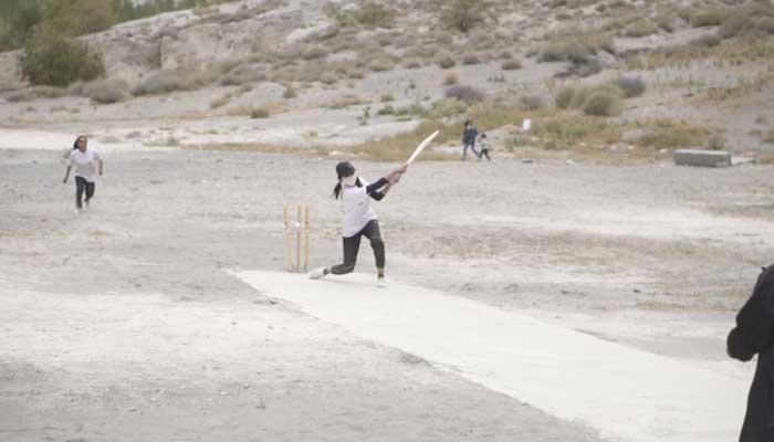 A girl plays an aggressive shot during a cricket tournament.