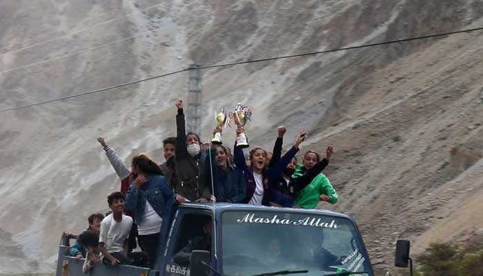 The victors of the tournament celebrate atop a vehicle with their trophies.