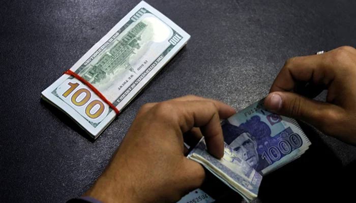 A currency dealer is seen counting Rs1,000 notes while a stack of dollar is placed on the table. — AFP/File