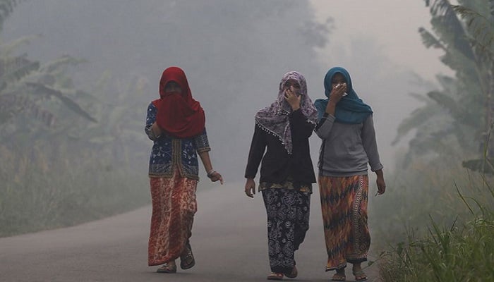 Los aldeanos caminan por una calle mientras la niebla envuelve el pueblo de Pulau Mentaro en Muaro Jambi, en la isla indonesia de Sumatra, 15 de septiembre de 2015. Foto: Reuters