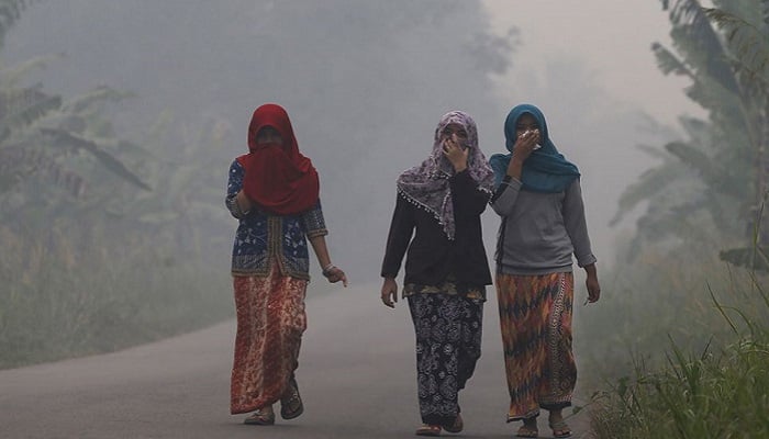 Villagers walk on a street as the haze shrouds Pulau Mentaro village in Muaro Jambi, on the Indonesian island of Sumatra, September 15, 2015. Photo: Reuters