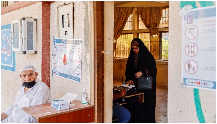 A woman scans her finger to verify her identity before voting at a polling station during the parliamentary election, in Kerbala, Iraq, October 10, 2021. REUTERS/Abdullah Dhiaa Al-deen.