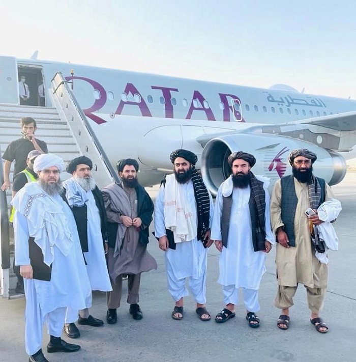 Taliban delegates stand in front of a Qatar Airways plane in an unidentified location in Afghanistan, in this handout photo uploaded to social media on October 8, 2021. Picture uploaded on on October 8, 2021. Social media handout/via REUTERS