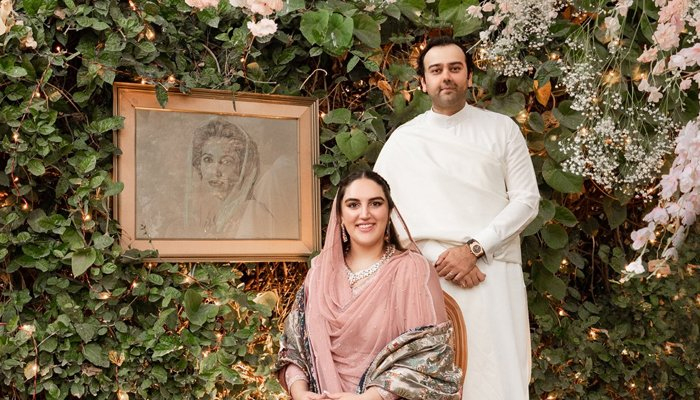 Bakhtawar Bhutto-Zardari and her fiancé, Mahmood Choudhary, pose for a photo against a backdrop of greenery and a picture of her late mother and former Pakistani prime minister, Benazir Bhutto, in Karachi, Pakistan, November 27, 2020. Twitter/Bakhtawar B-Zardari