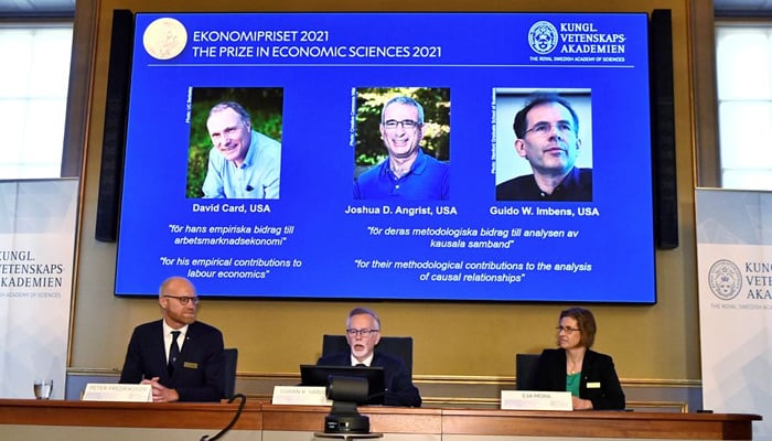 Royal Swedish Academy of Sciences Secretary General Goran K. Hansson and members of the academys Economic Sciences Prize Committee 2021 Peter Fredriksson and Eva Moerk announce the Sveriges Riksbank Prize in Economic Sciences in Memory of Alfred Nobel 2021 as photographs of the winners David Card, Joshua Angrist and Guido Imbens are presented on a screen during a news conference at the academy, in Stockholm, Sweden, October 11, 2021. — Reuters