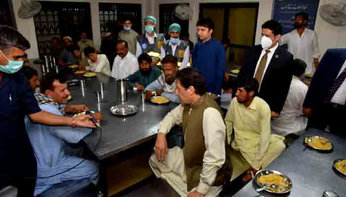 PM Imran Khan talking to people having their meal at Panagah. File photo