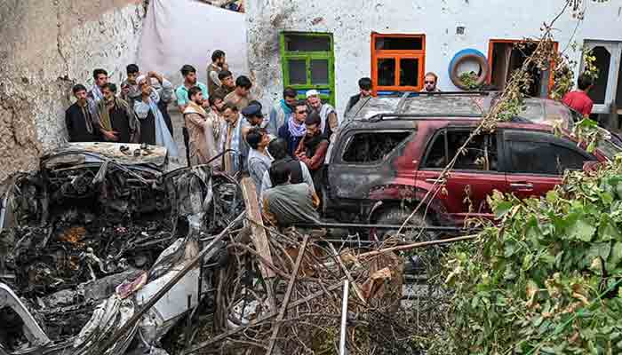 Afghan residents and family members of the victims gather next to a damaged vehicle inside a house, a day after a US drone airstrike in Kabul, on August 29. — AFP