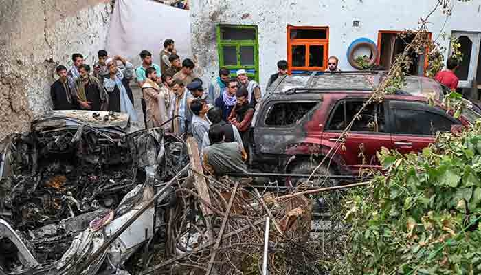 Afghan residents and family members of the victims gather next to a damaged vehicle inside a house, a day after a US drone airstrike in Kabul, on August 29. — AFP