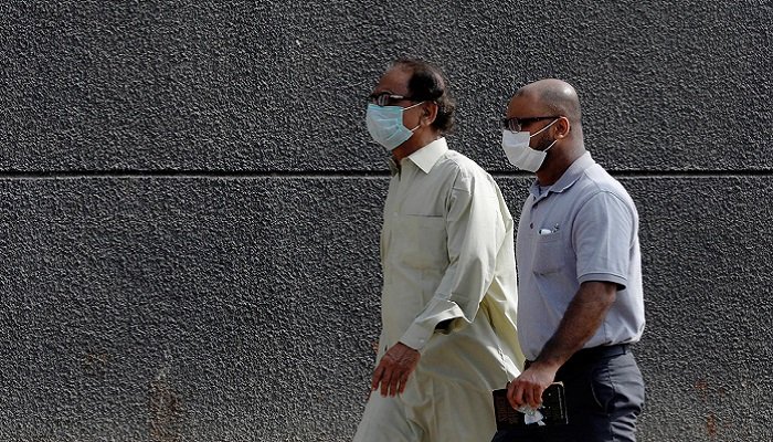 Men walk with face masks as a preventive measure against coronavirus along a sidewalk in Karachi, Pakistan. Photo: Reuters