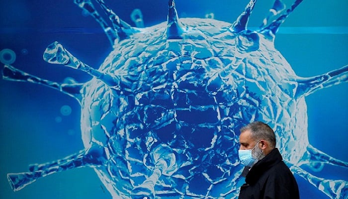 A man wearing a protective face mask walks past an illustration of a virus outside a regional science centre amid the coronavirus disease (COVID-19) outbreak, in Oldham, Britain. Photo: Reuters