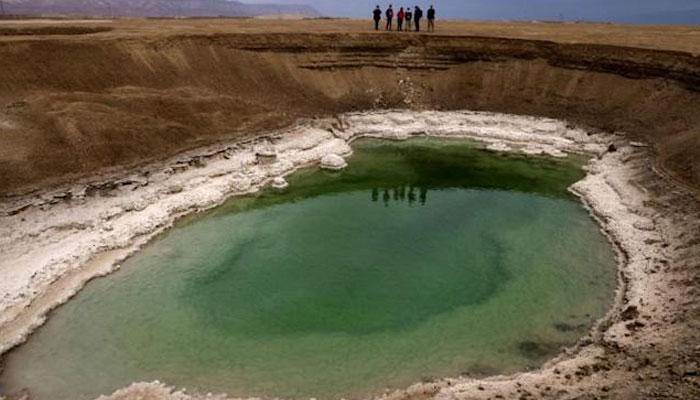 Hikers walk next to sinkholes in the southern part of the Dead Sea. AFP