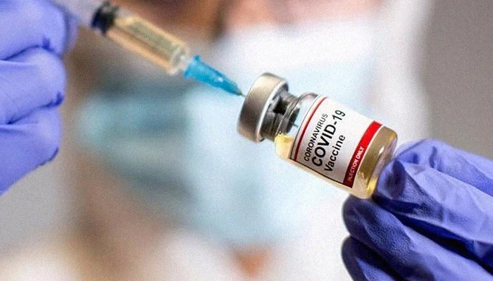 Seorang wanita memegang botol kecil — berlabel Vaksin Coronavirus COVID-19 — dan jarum suntik medis, 30 Oktober 2020. Foto: Reuters