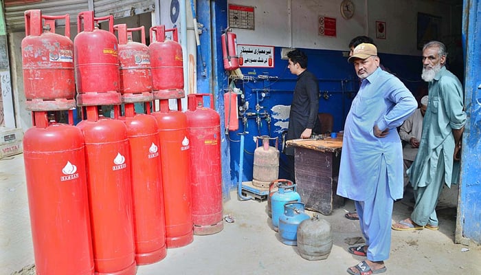 People getting their LPG cylinders refilled from a shop at Station Road in Hyderabad on October 24, 2021. — APP/File