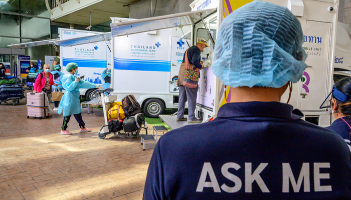 Seorang pegawai bandara membantu penumpang melewati area kedatangan di Bandara Internasional Phuket saat Thailand menyambut rombongan wisatawan pertama yang divaksinasi penuh terhadap virus corona Covid-19 tanpa karantina di Phuket pada 1 November 2021. — AFP