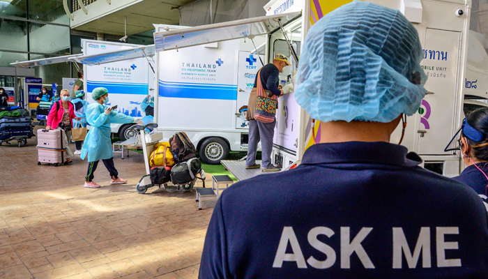 An airport employee assists passengers through the arrival area at Phuket International Airport as Thailand welcomes the first group of tourists fully vaccinated against the Covid-19 coronavirus without quarantine in Phuket on November 1, 2021. — AFP