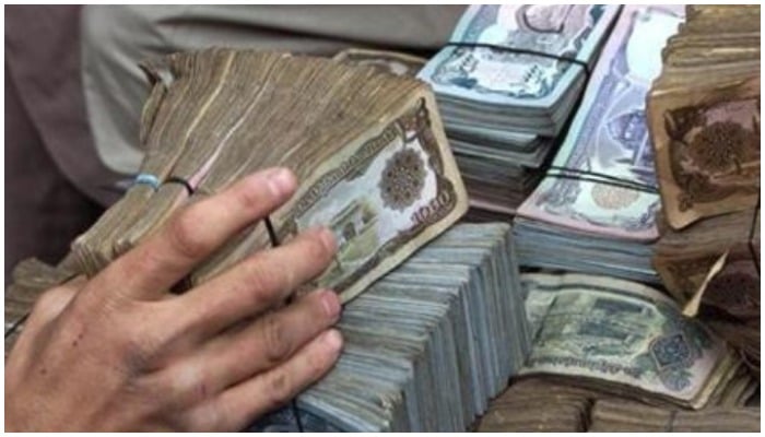 An Afghan money dealer adjusts banknotes of 10,000 Afghani at the open-air Shahzada money market in Kabul on February 18, 2002. REUTERS/Mario Laporta/Files.