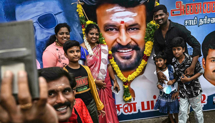 Fans take selfies with a billboard showing Bollywood star Rajinikanth ahead of the release of his film Annaatthe. AFP
